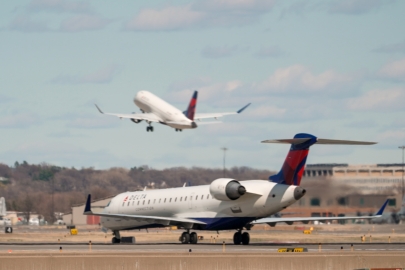 A Delta plane on a runway with a plane taking off in the background.