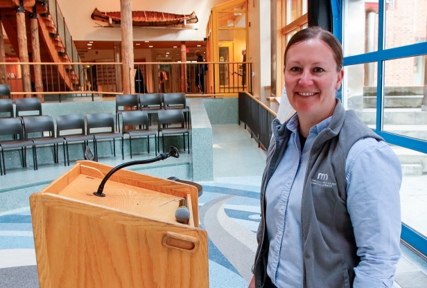 A woman standing in front of a lectern smiling at the camera.
